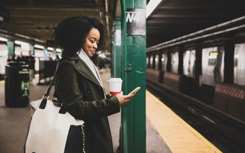 Find your perfect fit at Ovation woman with a cup of coffee texts on subway station platform